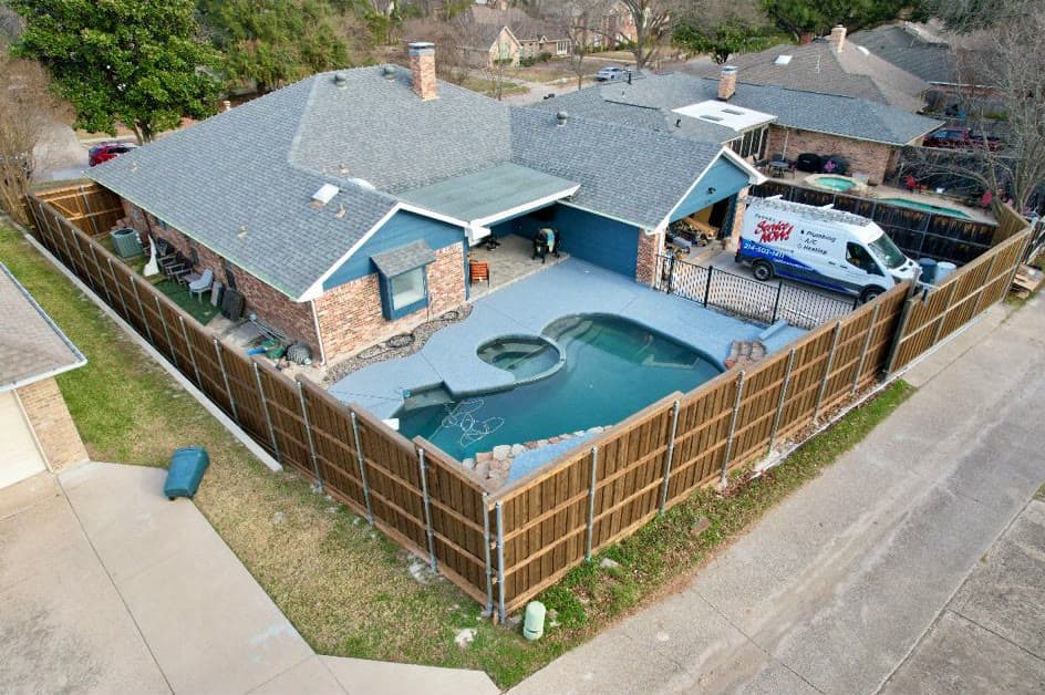 Aerial view of the same backyard pool with a refinished natural-tone cedar privacy fence
